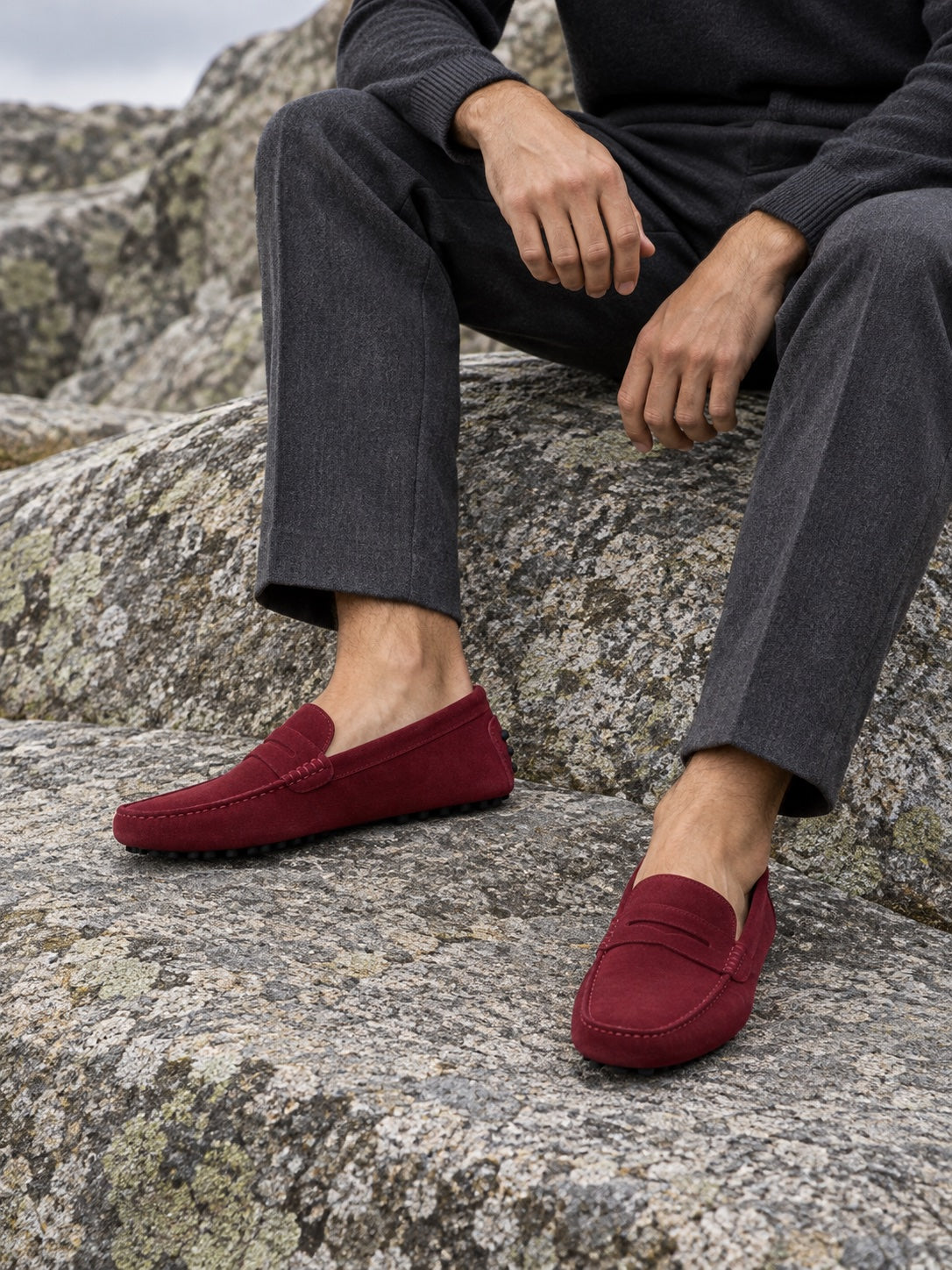 Mocasines de ante burdeos con pantalón gris sobre roca de granito
